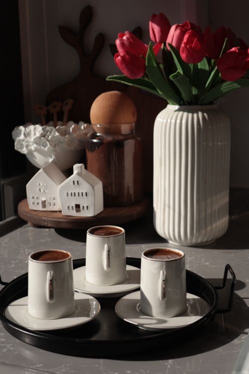 Free A cozy morning scene with coffee cups, red tulips, and ceramic decor on a kitchen counter. Stock Photo