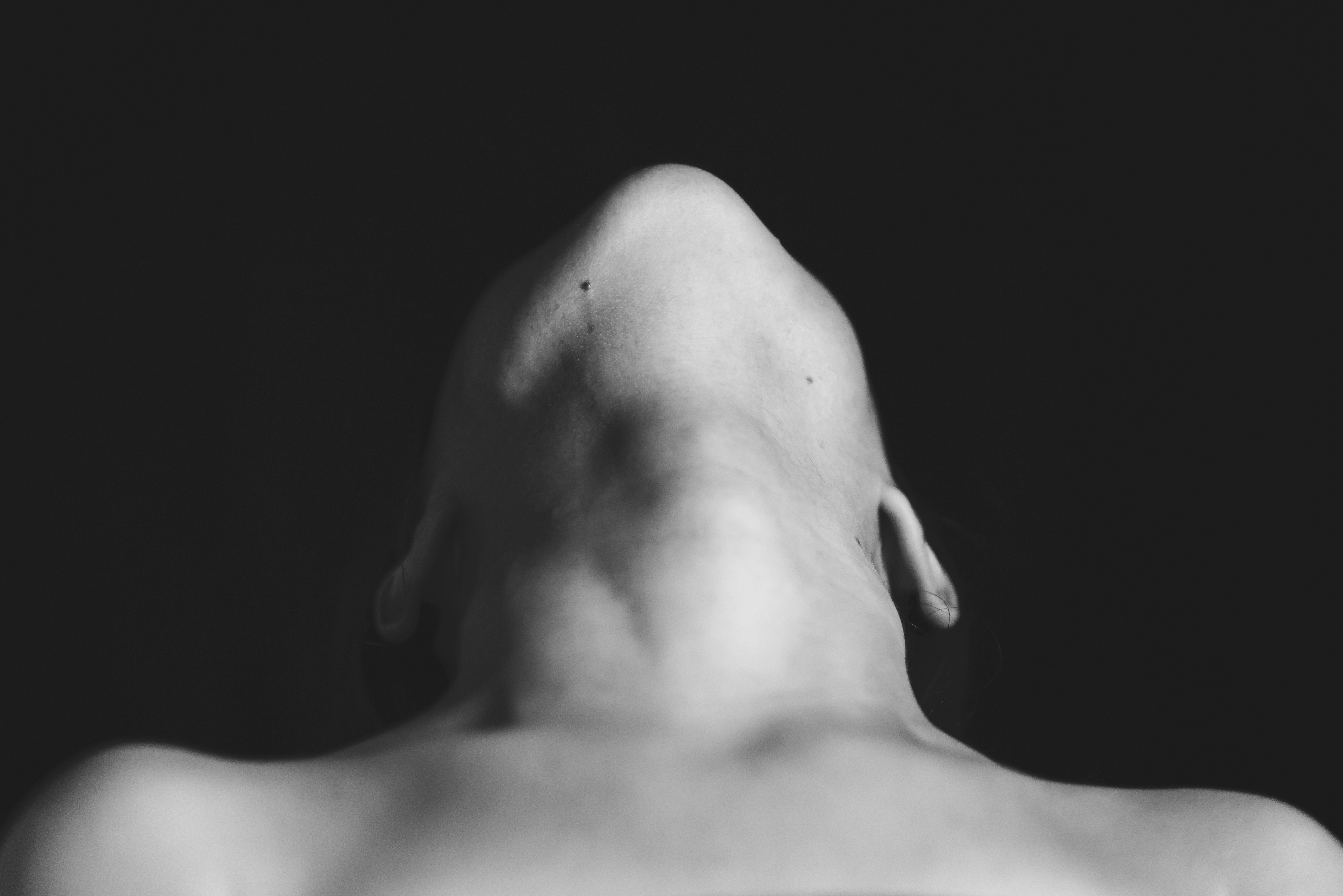 Black and white artistic portrait of a person with their head tilted back, showcasing the neck's curves.