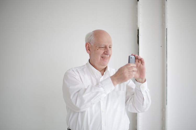 Cheerful Bald Man Taking Photo On Smartphone