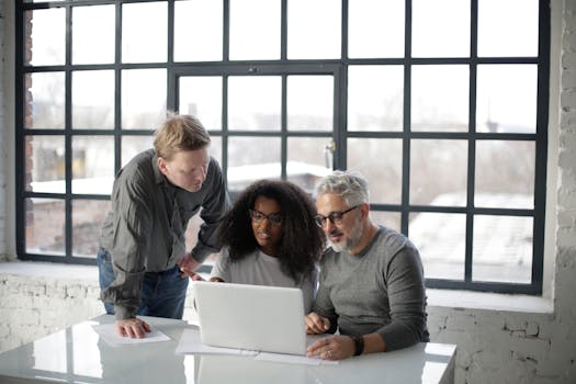 Multiracial team collaborating on a project in a bright modern office setting with natural light.