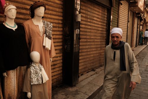 Free An elderly man walks past mannequins on a quiet street in Cairo, Egypt. Stock Photo