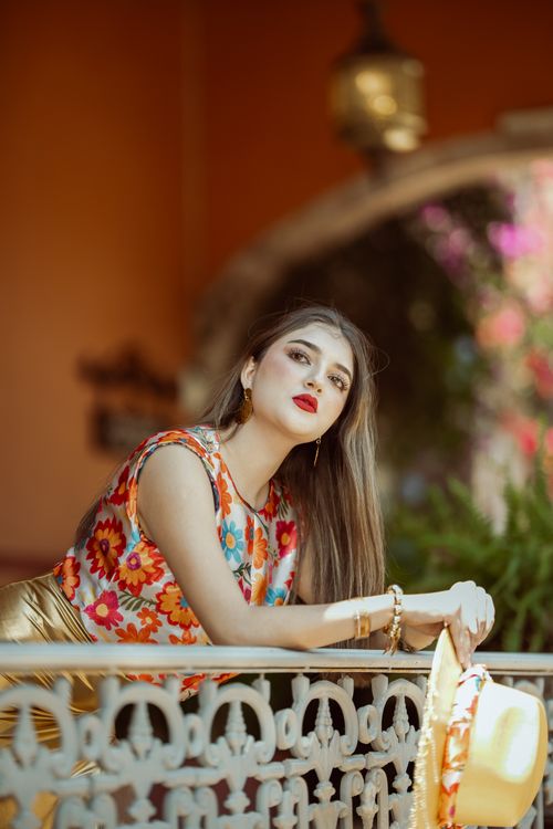 Free Stylish woman in floral attire leaning on a decorative balcony in León, Mexico. Stock Photo