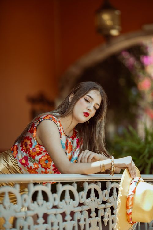 Free Stylish young woman in colorful Mexican dress poses gracefully on a balcony in León, México. Stock Photo