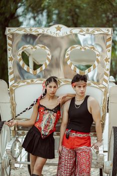 Fashionable couple posing with ornate carriage in León, Mexico, showcasing traditional attire.