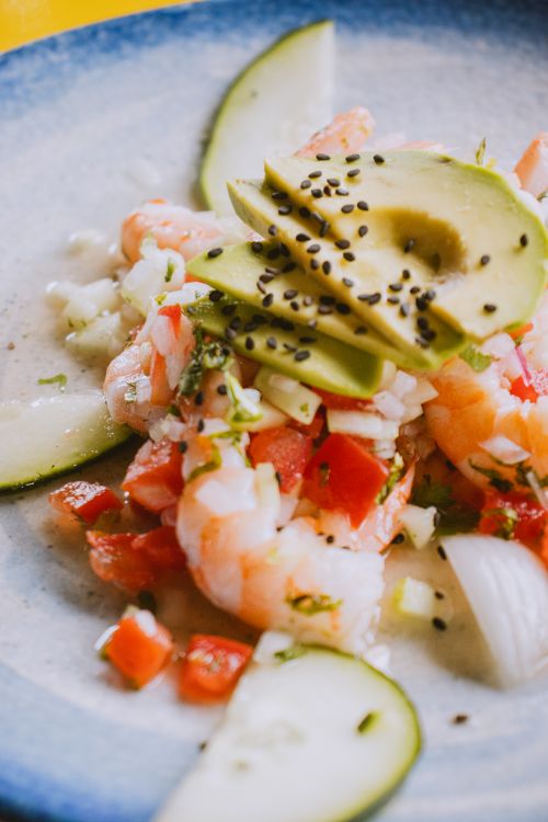 Free Vibrant shrimp ceviche topped with avocado, cucumber, and black sesame seeds on a plate. Stock Photo