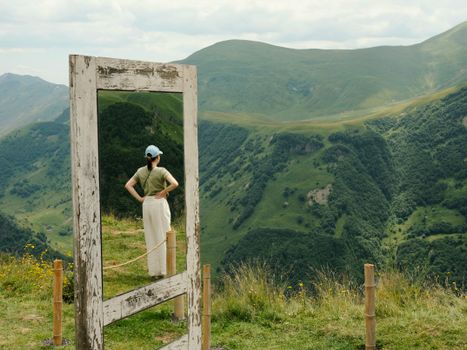 A person stands before an outdoor mirror reflecting stunning Georgian mountain views.