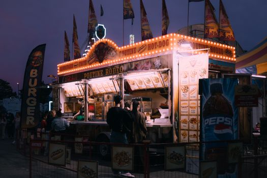 Explore a colorful food truck at a lively night carnival offering diverse snacks and vibrant atmosphere.