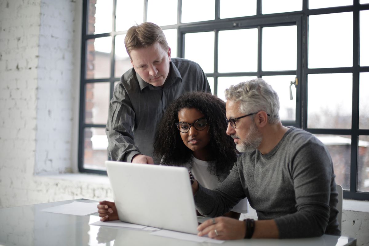 Three colleagues reviewing a request together at a laptop