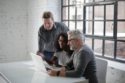Free Focused multiethnic colleagues surfing computer while African American woman explaining details of project and gesticulating Stock Photo