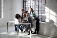 Team of creative colleagues using laptop for working on project