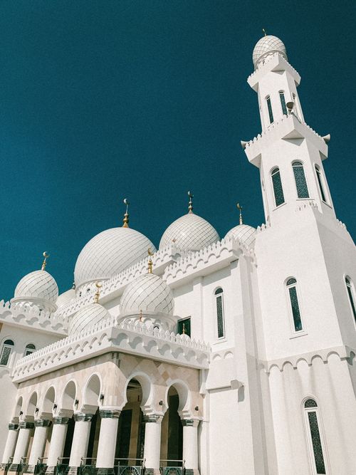 Free Stunning view of a white mosque with domes and minaret against a clear blue sky. Stock Photo
