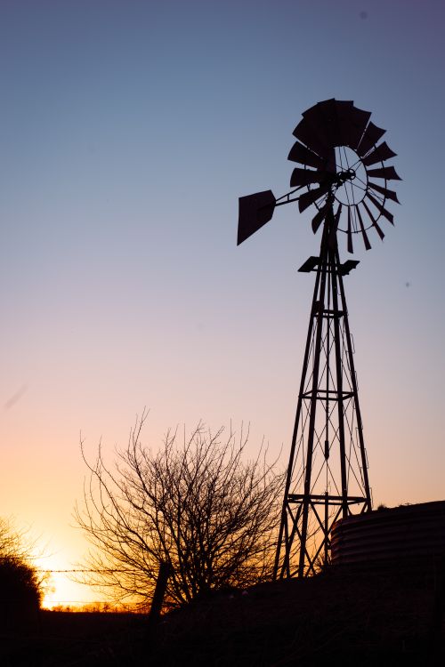 Free Silhouette of a rustic windmill against a vibrant sunset sky. Stock Photo