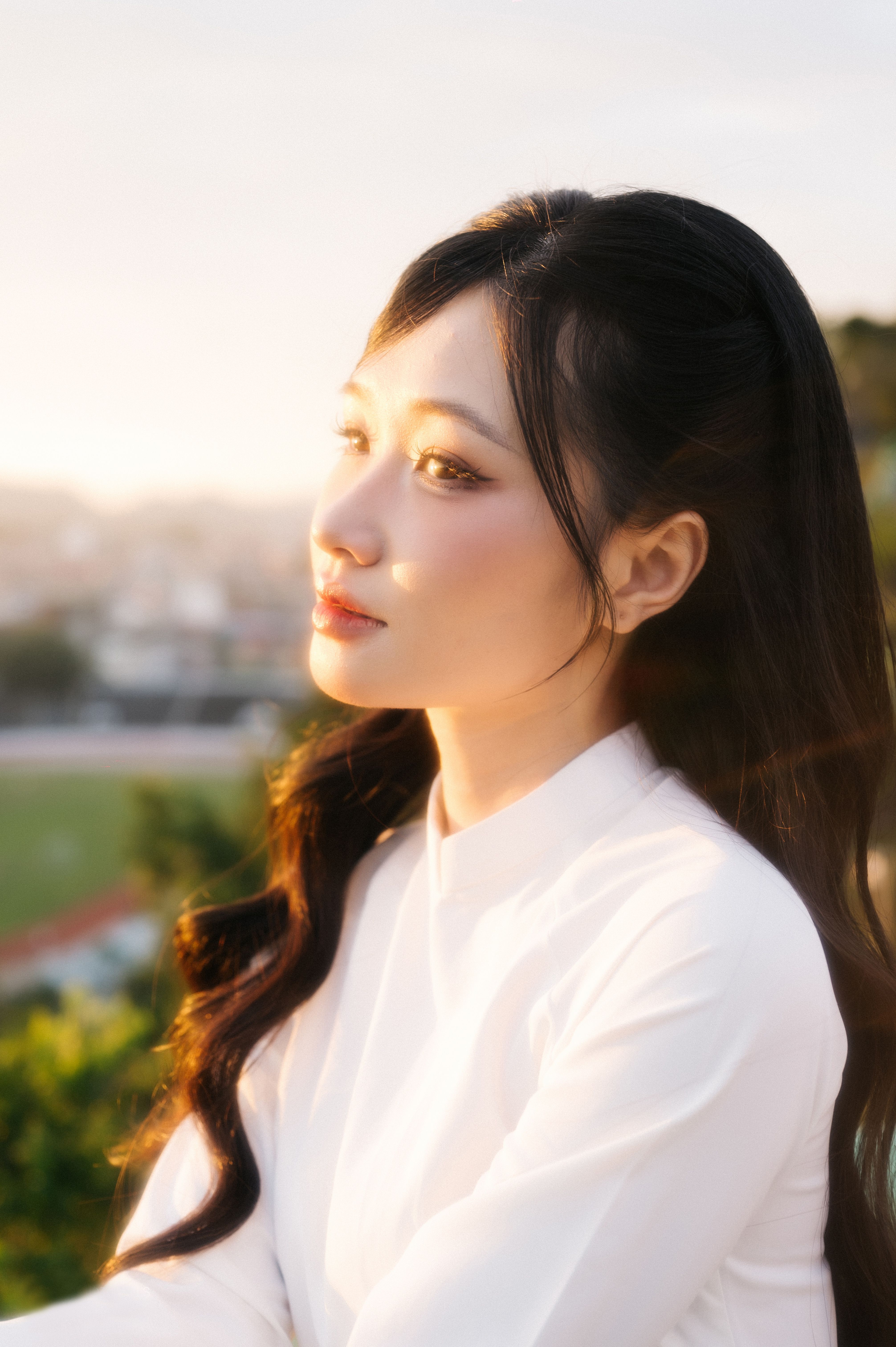 Elegant portrait of a woman in a white dress, basked in warm sunset light.