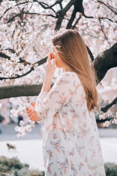 闲暇时分，一位平静的年轻女子在花园中侧身而立，周围是树木与鲜花