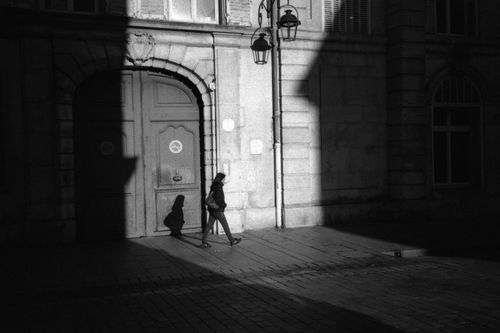 Free A silhouette of a person walking past an old building in Nancy, France, captured in dramatic shadow. Stock Photo