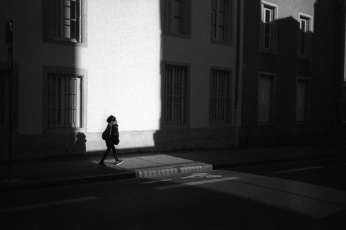 Free Black and white photo of a person walking on a street in Nancy, France, in striking shadows. Stock Photo
