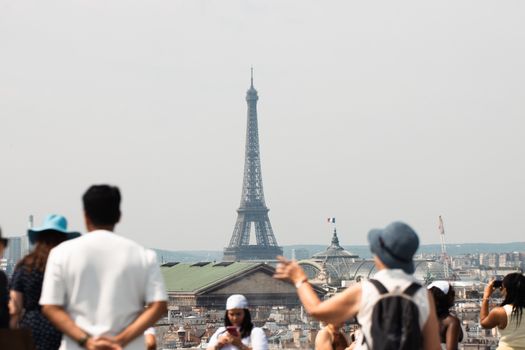 A view of the Eiffel Tower with tourists in the foreground, capturing a sunny day in Paris.