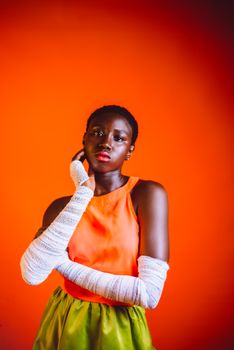Artistic portrait of a woman in bright attire against a vivid orange background, showcasing bold fashion.