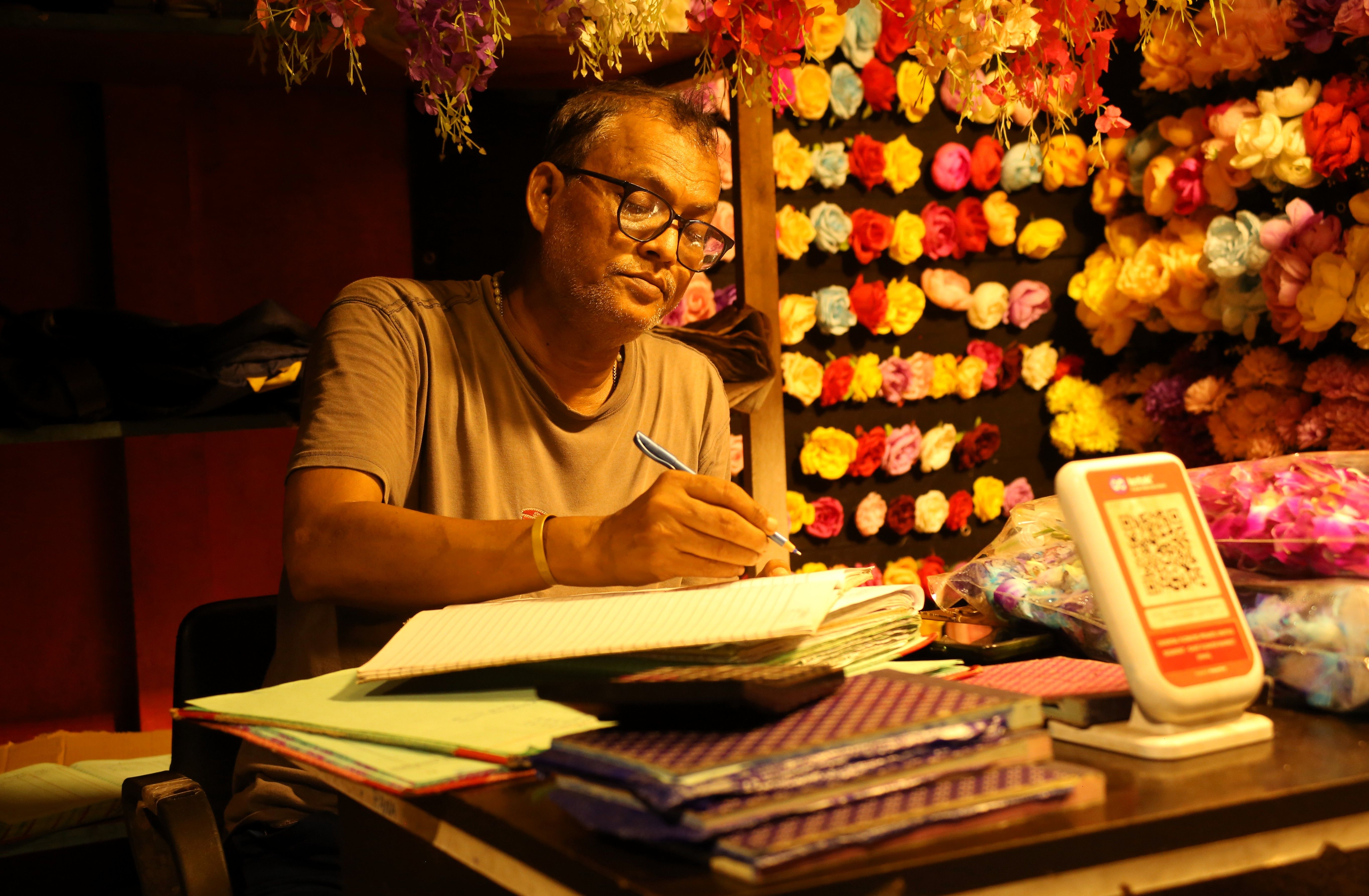 क्रिकेट प्रेमी का नोटबुक में भारत बनाम ऑस्ट्रेलिया मैच आँकड़े लिखना, पास में लैपटॉप और स्कोरकार्ड