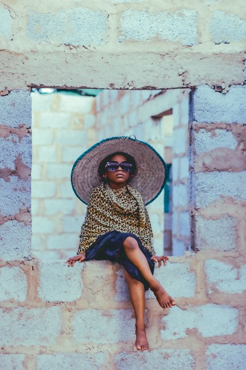 Free Charming young girl in sunglasses, a leopard print scarf and sun hat, posing outdoors in Abuja, Nigeria. Stock Photo
