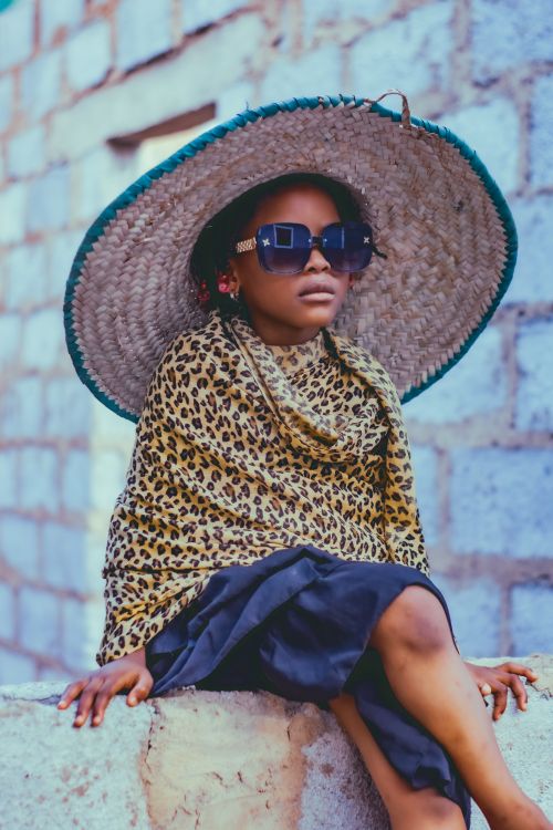 Free A child wearing a leopard print shawl, large sunhat, and sunglasses in Abuja, Nigeria. Stock Photo