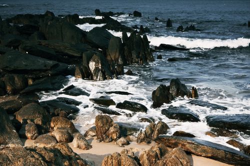 Free A serene view of rugged coastal rocks with waves crashing on the shore, perfect for mood and nature visuals. Stock Photo