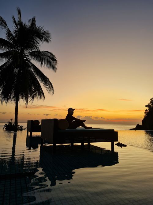 Free Silhouette of relaxed person at poolside during sunset with palm view. Stock Photo