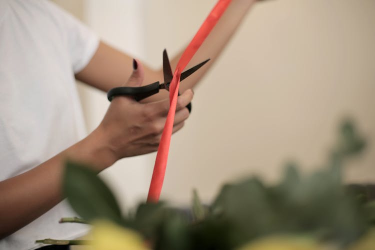 Crop Woman Cutting Ribbon For Bouquet