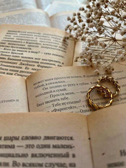 Free A gold ring rests on vintage book pages with dried flowers, creating a nostalgic ambiance. Stock Photo