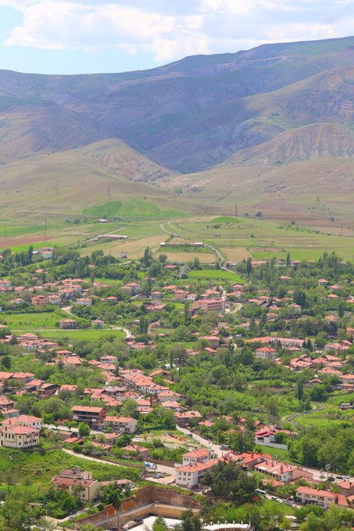 Free A picturesque aerial view of a rural village nestled in lush green hills. Stock Photo