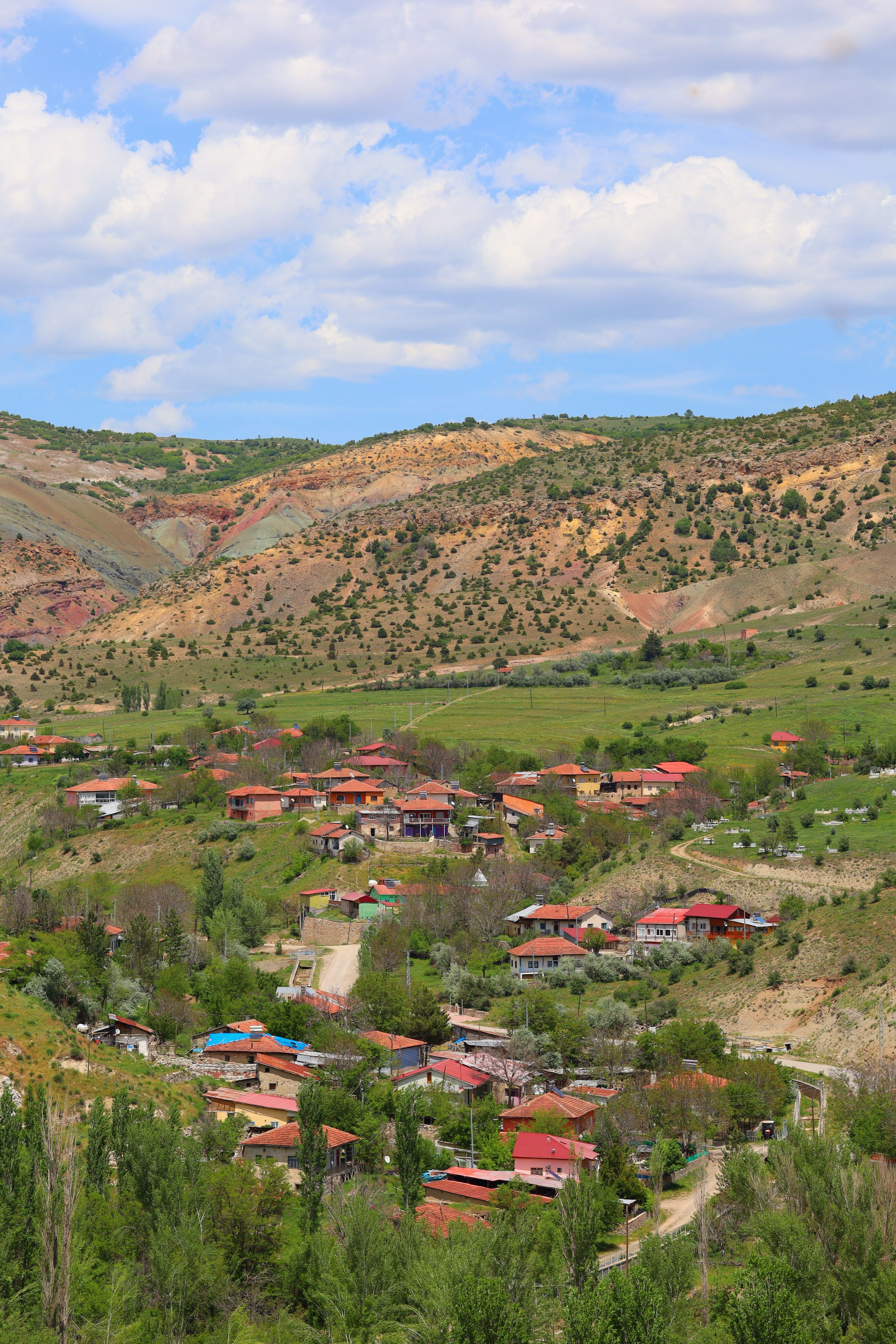 A vibrant village nestled within a mountainous valley under a bright blue sky.