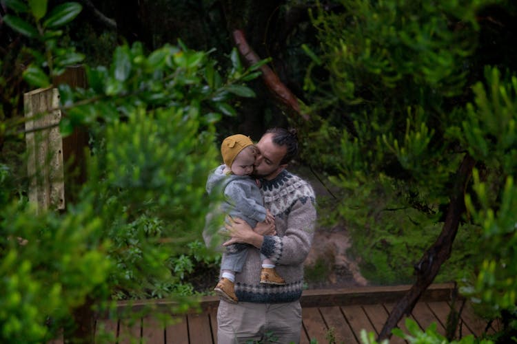 Happy Father Kissing Child In Dense Forest