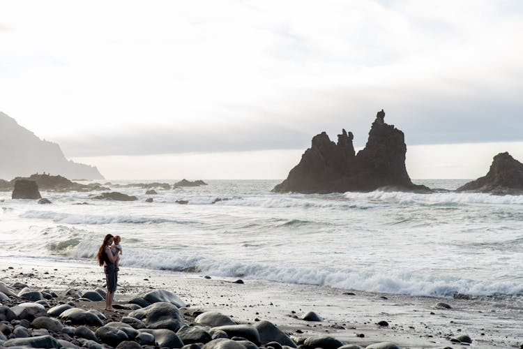 Lonely Woman With Child On Rocky Coast