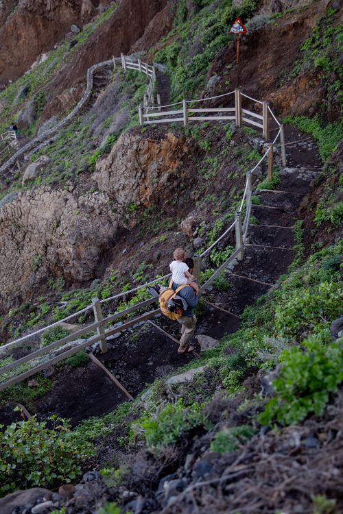 Free From above of anonymous father holding kid on shoulders while coming down on stairs Stock Photo