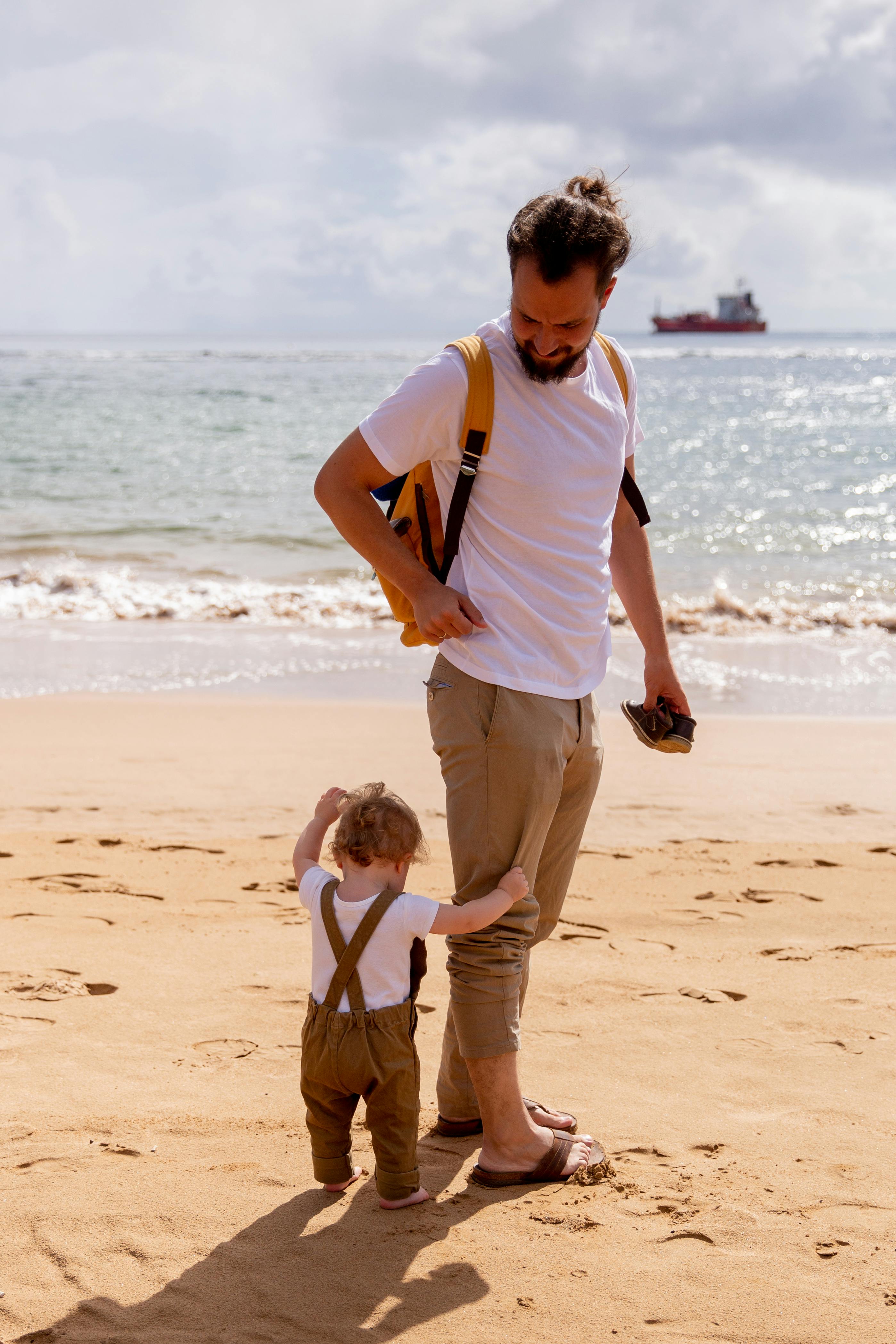 happy dad looking at toddler on sandy beach