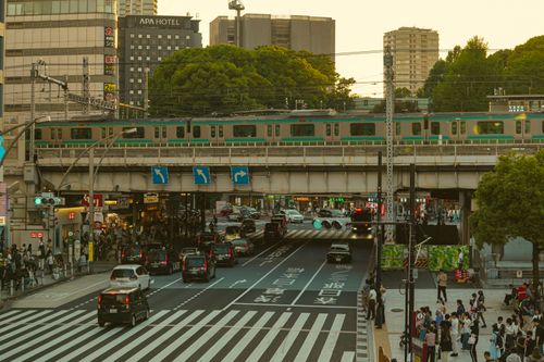 Free A bustling city scene in Tokyo showing a train overpass, traffic, and pedestrians. Stock Photo