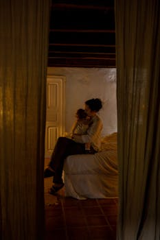 室内场景温馨，母亲抱着孩子躺在床上，传递着温暖和爱意