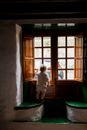 Adorable toddler standing alone near window in rural interior house