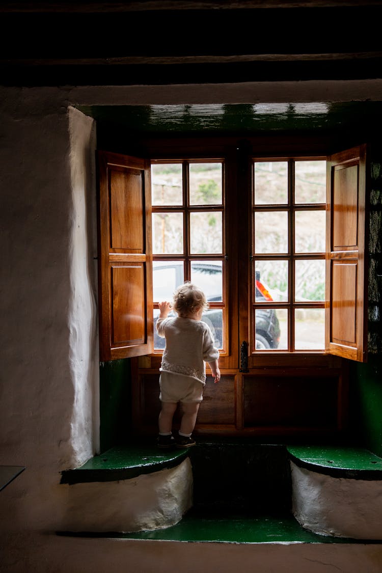 Adorable Toddler Standing Alone Near Window In Rural Interior House