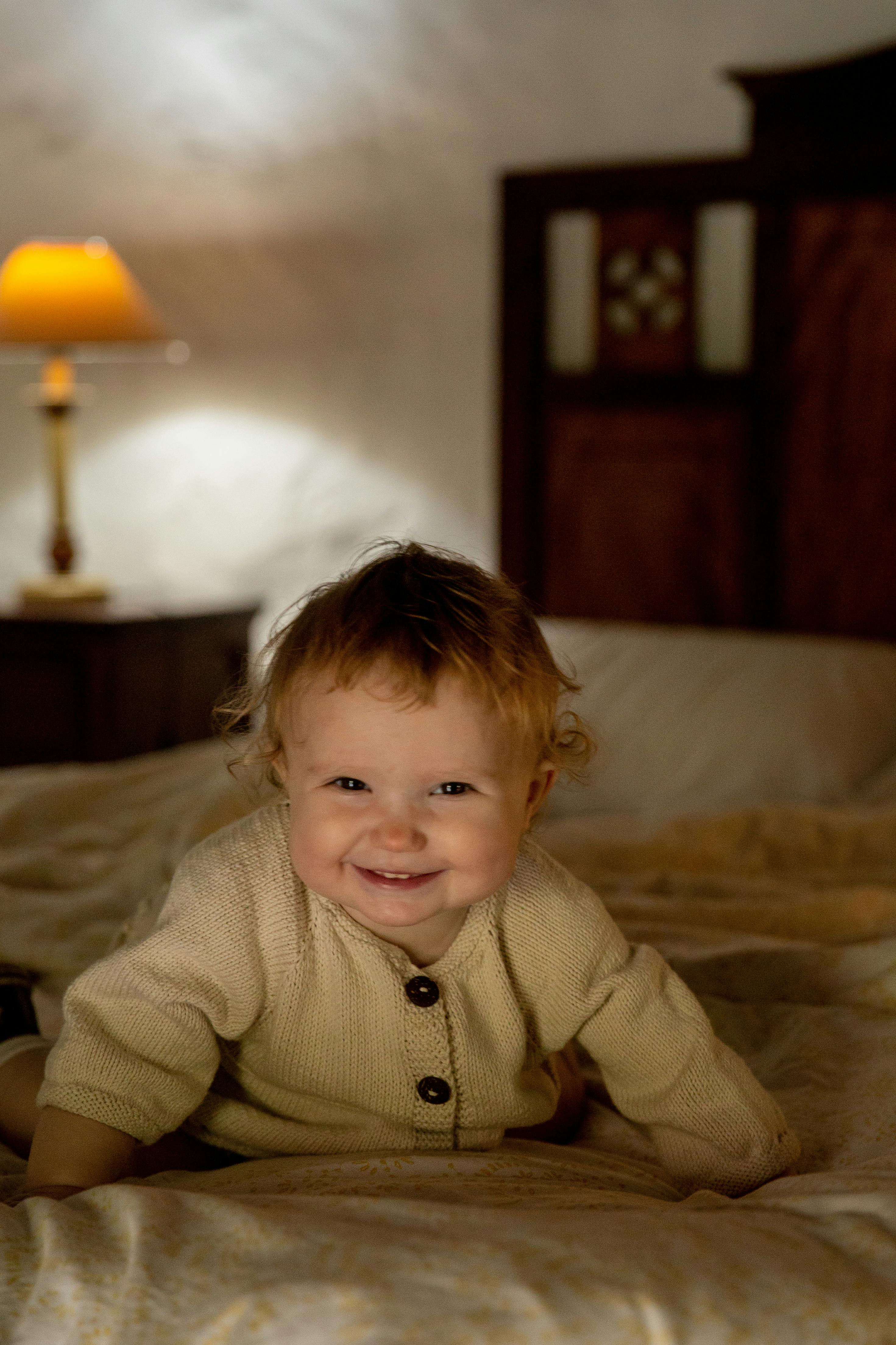 happy little child lying on bed in rural interior house