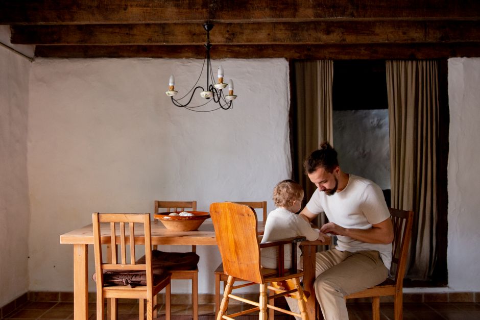 Un padre y su hijo compartiendo un momento juntos en una mesa de comedor en un interior rústico.