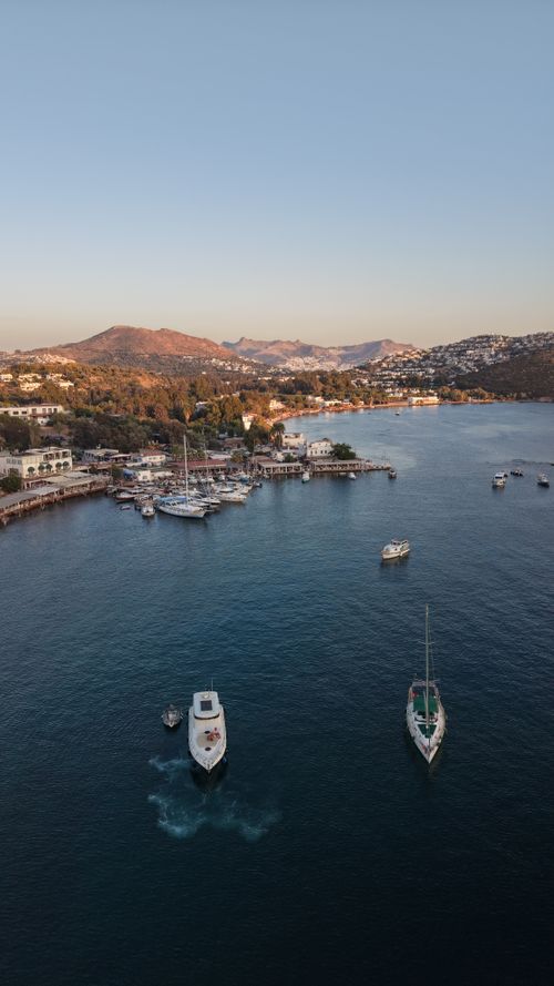Free Stunning aerial view of Bodrum coastline in Türkiye with boats and lush hills at dusk. Stock Photo