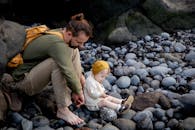 父女俩在布满岩石的海滩上，享受着亲密的时光，四周是石头与自然环绕