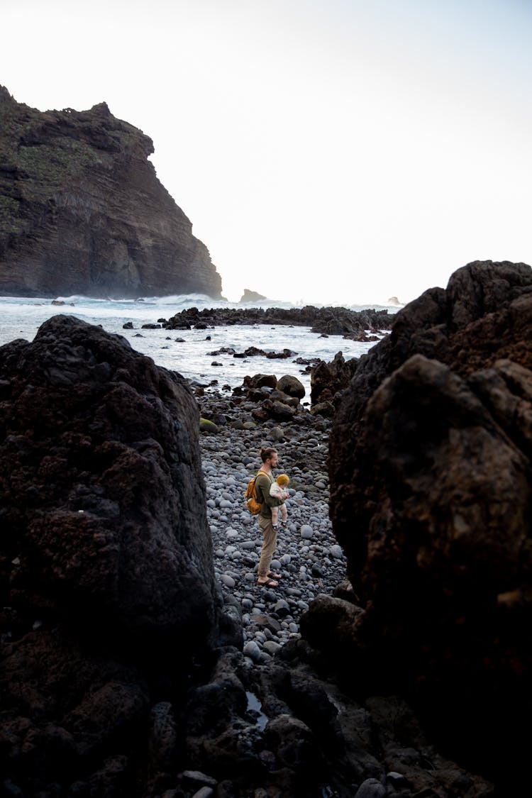 Father And Child Standing On Rocky Shore