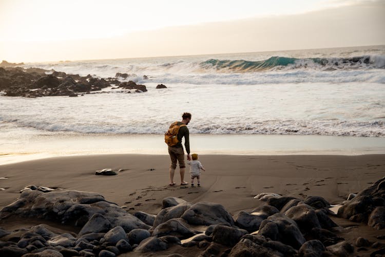 Unrecognizable Young Father With Little Child Walking On Beach