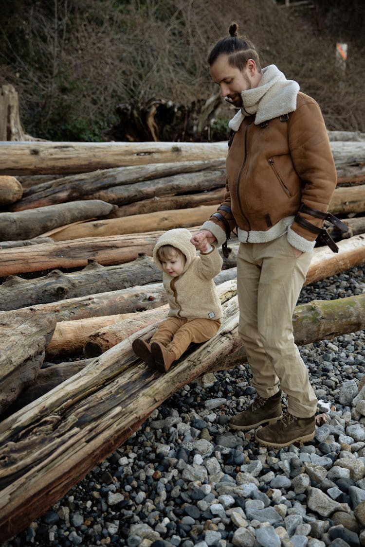 Positive Father And Little Daughter Playing On Log On Stony Ground