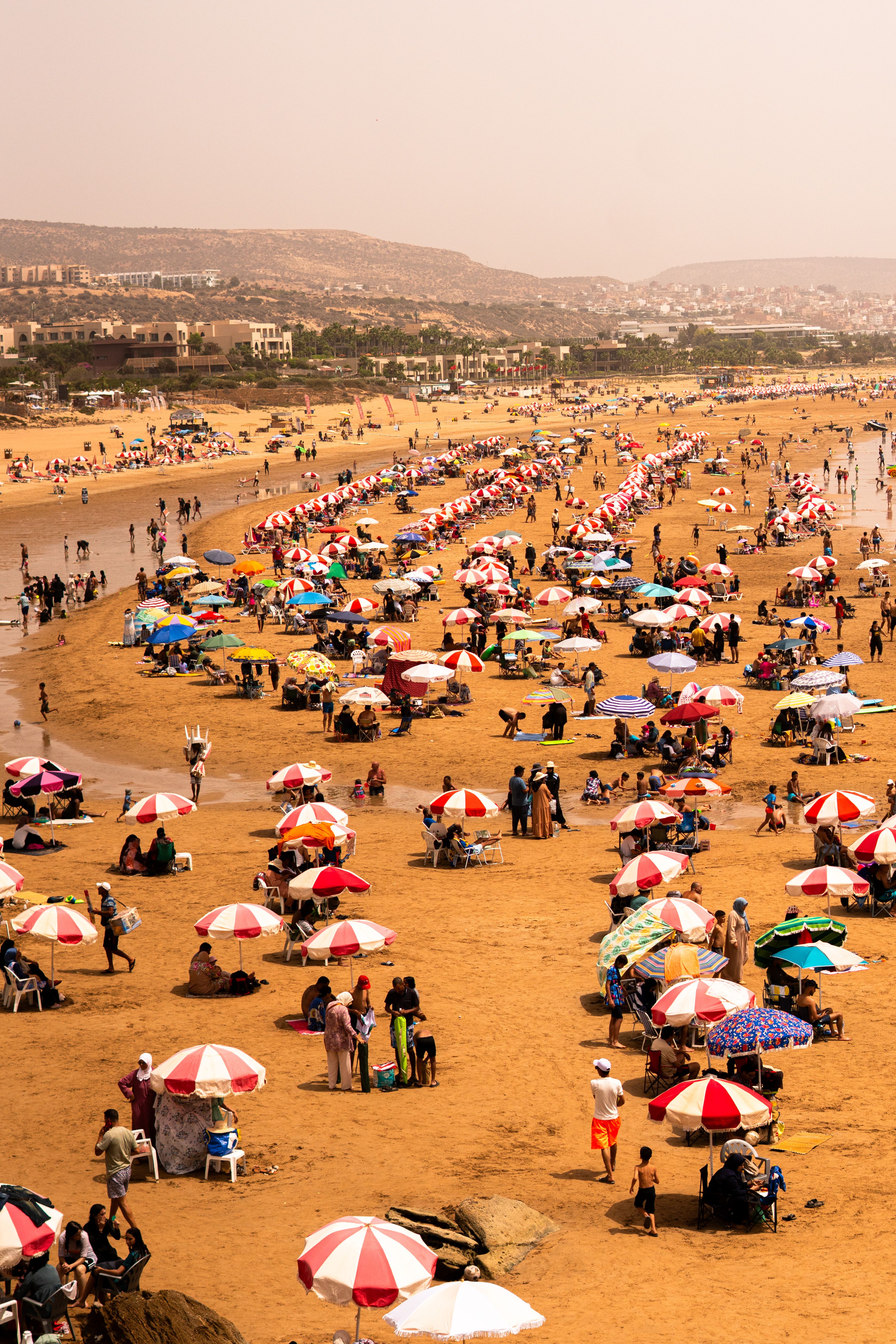 Busy Agadir beach with colourful umbrellas and swimmers