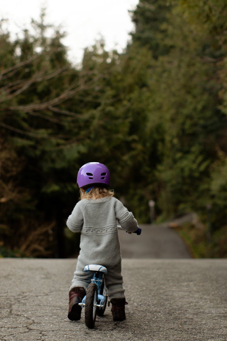 Anonymous Kid In Helmet Riding Run Bike On Pavement In Countryside