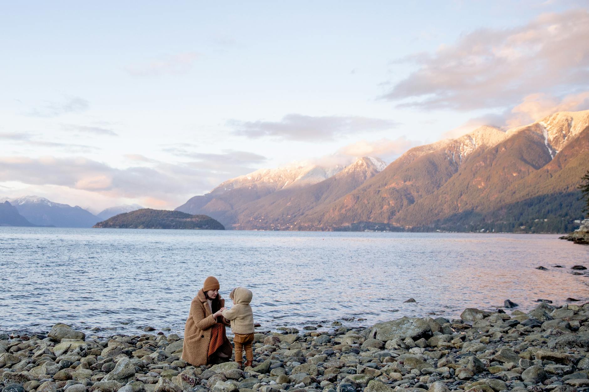 Mother and kid standing on rocky shore and looking at each other