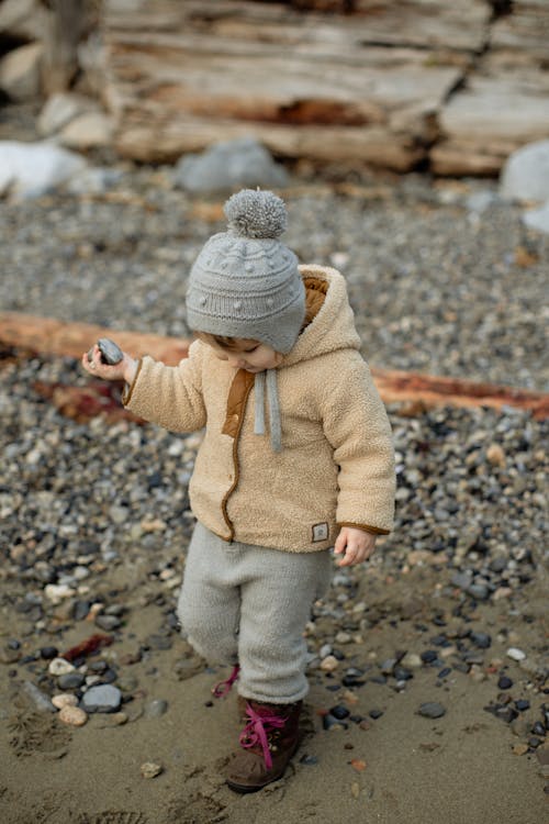 Curious little girl in warm clothing walking on winter beach